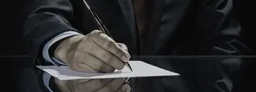 A person writing on paper with a pen.